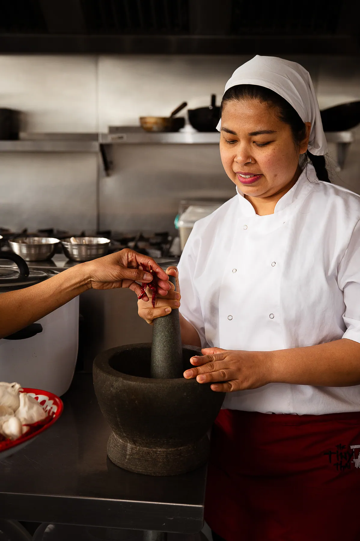 A chef working curry paste in a pestle and mortar