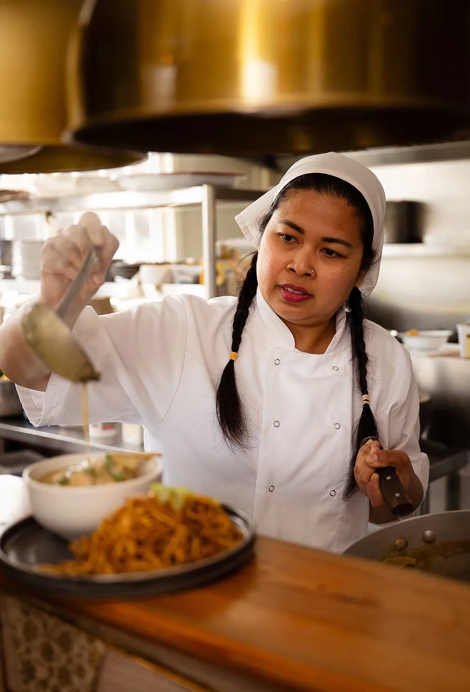 A chef plating up a dish in The Tiny Thai kitchen