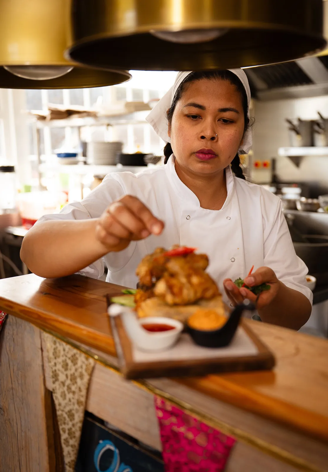 A chef finishing a plate of starters at the pass