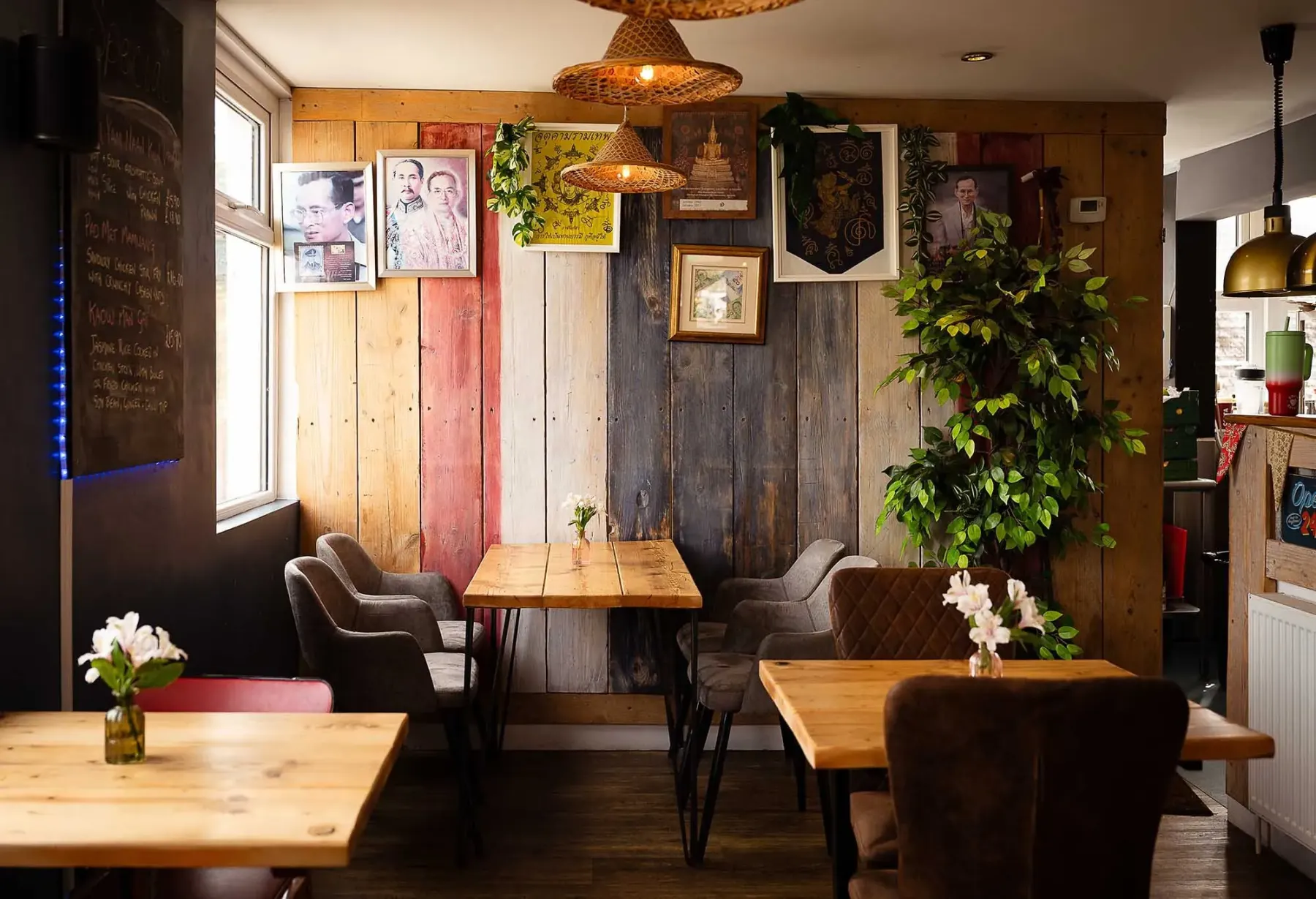 The Wadebridge dining room: timber walls, Thai prints and rattan lamps over wooden tables