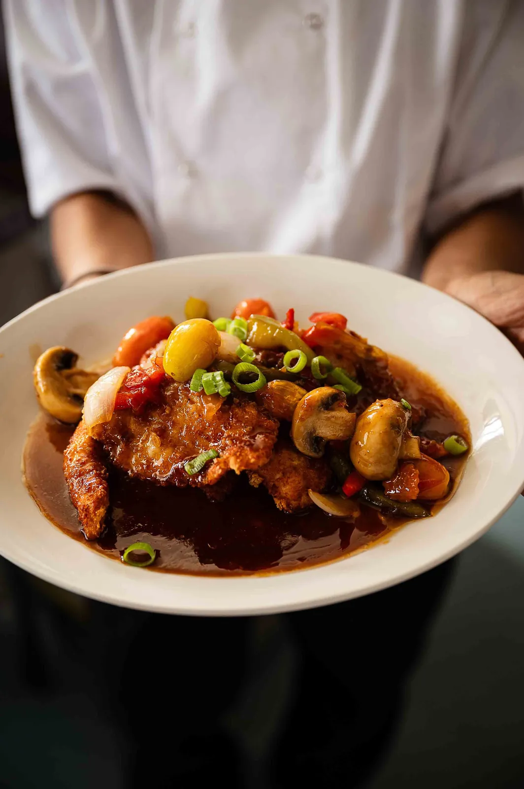 Panko-coated chicken with sweet and sour sauce, held by a chef